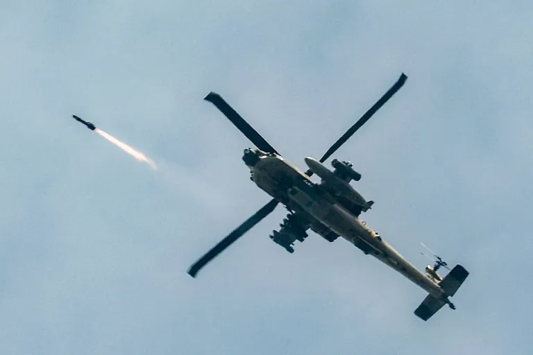 An Israeli Air Force AH-64 Apache attack helicopter fires rockets while flying along the border between northern Israel and southern Lebanon on March 18, 2026. The Israeli military said it planned to strike bridges and crossings over the Litani River in southern Lebanon on March 18 to disrupt what it said were Hezbollah arms-smuggling routes. Lebanon was drawn into the Middle East war on March 2 when militant group Hezbollah launched rockets into Israel to avenge the killing of Iran's supreme leader. (Photo by Jalaa MAREY / AFP via Getty Images) /