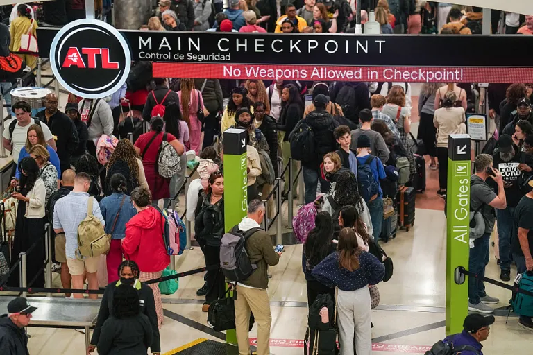Travelers wait in line at a Transportation Security Administration (TSA) checkpoint at Hartsfield-Jackson Atlanta International Airport (ATL) in Atlanta, Georgia, US, on Friday, March 20, 2026. Travelers have encountered long lines snaking through terminals during the partial government shutdown, prompting airports to warn passengers to show up hours before their flight. Photographer: Elijah Nouvelage/Bloomberg via Getty Images