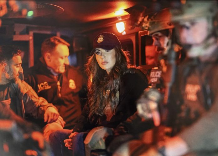 A picture taken of a picture hanging in former Homeland Security Secretary Kristi Noem's office within one agency building in Washington shows Noem at the center of a group of federal law enforcement. The federal police are out of focus and Noem, wearing an ICE ball cap and bulletproof vest, is in focus as she looks past the camera. (Courtesy image)