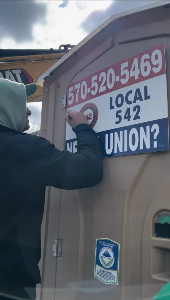 A man signing his name on a Port-a-John prop
