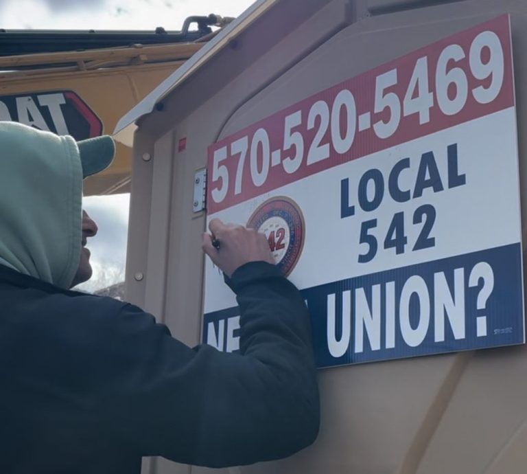 A man signing his name on a Port-a-John prop.
