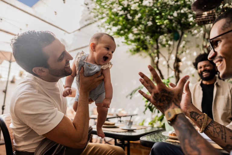 Father playing with daughter during friends meeting at coffee shop