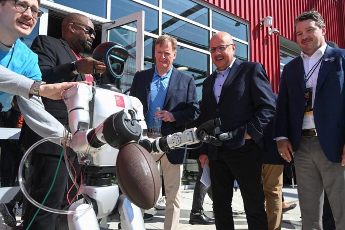 Carnegie Mellon University’s President Farnam Jahanian, second from right, shows NFL Commissioner Roger Goodell, center, a robot that throws a football during a tour of CMU’s Robotics Innovation Center at Hazelwood Green on Wednesday, April 22, 2026.