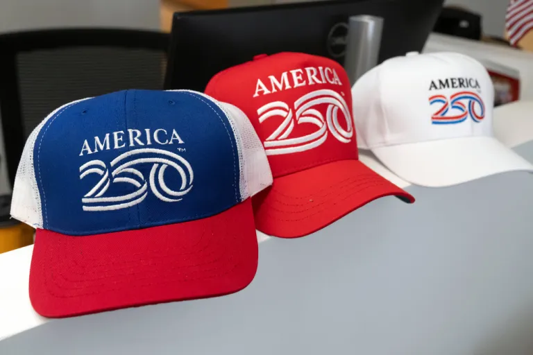 Themed caps are displayed at the offices of America250