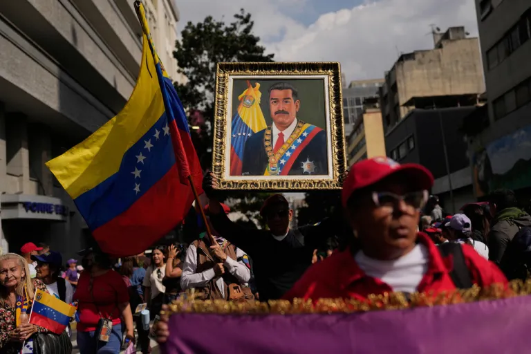 A government supporter holds an image of President Nicolas Maduro during a women's march to demand his return