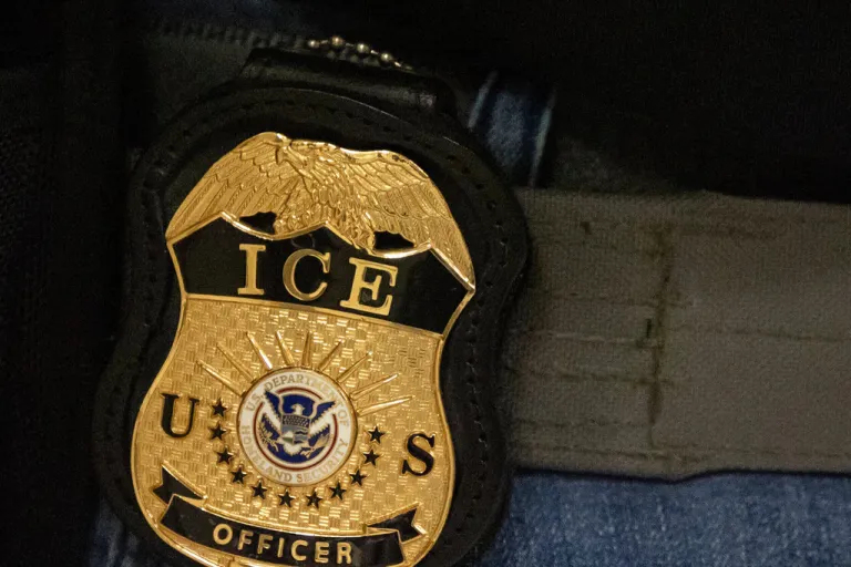 A federal agent wears an Immigration and Customs Enforcement badge