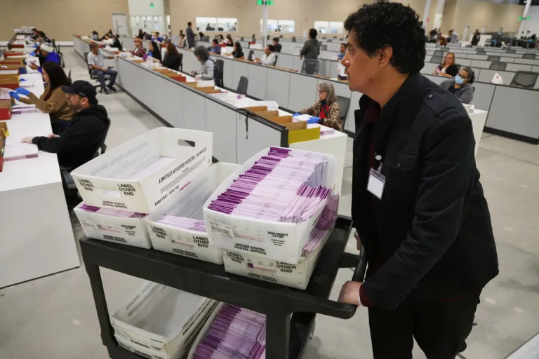 A worker pushes a cart of received mail ballots at the L.A. County Ballot Processing Center.