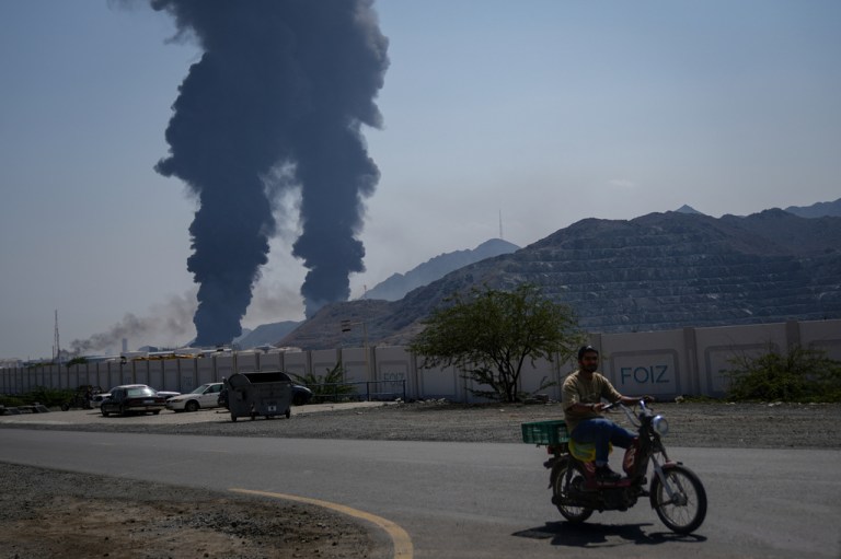 A man rides a motorcycle past an explosion in Iran