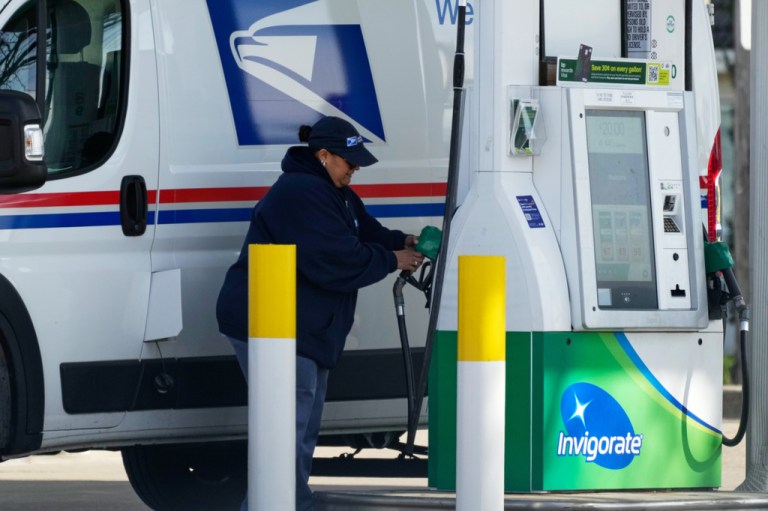 A woman holds a fuel pump nozzle to fill up a USPS vehicle's tank at a gas station, in Chicago, Tuesday, April 7, 2026. (AP Photo/Nam Y. Huh)