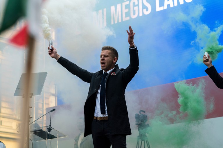 Péter Magyar stands on stage amid smoke in the colors of the Hungarian flag