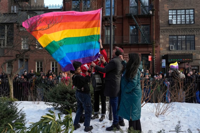 New York politicians and activists raise a rainbow flag on a pole in Christopher Park.