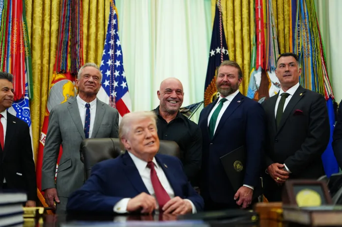 President Donald Trump smiles, joined by, from left, Dr. Marty Makary, commissioner of the Food and Drug Administration, U.S. Secretary of Health and Human Services Robert Kennedy Jr., Joe Rogan, Americans for Ibogaine CEO W. Bryan Hubbard and retired U.S. Navy Seal Marcus Luttrell in the Oval Office of the White House, Saturday, April 18, 2026, in Washington. (AP Photo/Julia Demaree Nikhinson)