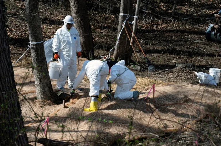Workers prepare to take soil samples where raw sewage flowed near the Potomac River.
