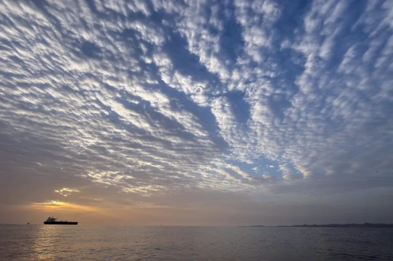 The sun rises behind a tanker anchored in the Strait of Hormuz.