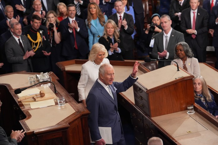 King Charles III waves from a congressional podium.