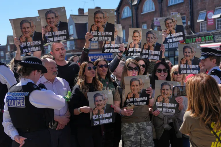 People in London carry signs protesting British Prime Minister Keir Starmer.