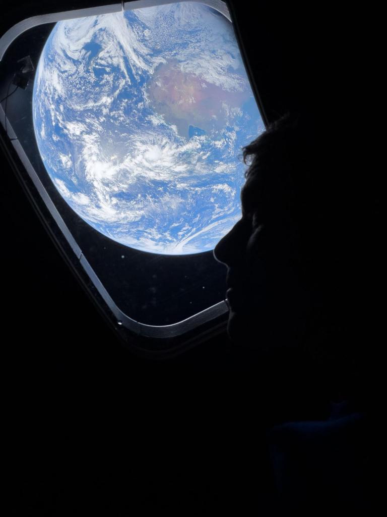 This image provided by NASA, astronaut and Artemis II mission specialist Christina Koch peers out of one of the Orion spacecraft's main cabin windows, looking back at Earth, as the crew travels towards the Moon on Thursday, April 2, 2026. (NASA via AP)