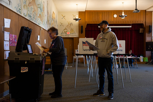 Volunteer election workers Anne Ketz, left, and David Gebhardt, cast absentee ballots at Lapham Elementary School during the spring election, April 7, 2026 in Madison, Wisconsin. The election includes a Wisconsin Supreme Court contest between Appeals Court judges Maria Lazar, backed by Republicans, and Chris Taylor, backed by Democrats, as well as local municipal and judicial elections and school referendum questions. 