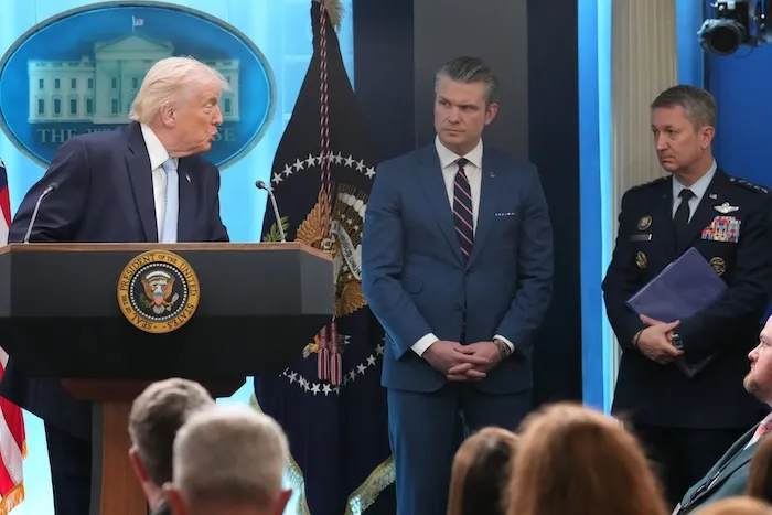 President Donald Trump looks to Defense Secretary Pete Hegseth and Chairman of the Joint Chiefs of Staff Gen. Dan Caine as he speaks with reporters during a news conference in the James Brady Press Briefing Room at the White House, Monday, April 6, 2026, in Washington. (AP Photo/Mark Schiefelbein)