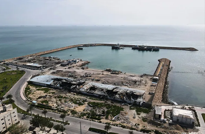 Backdropped by ships in the Strait of Hormuz, damage caused by airstrikes is seen on a fishing pier in the port of Qeshm island, Iran on April 13. (Asghar Besharati/AP)
