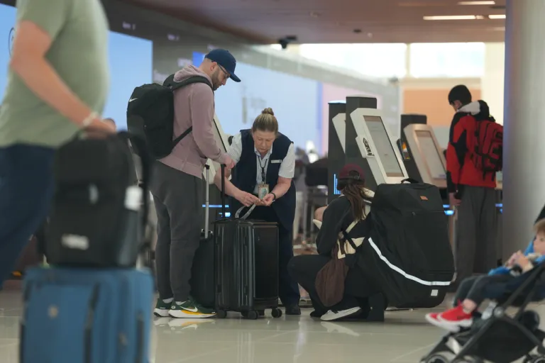 United Airlines ticketing agent, center, tags baggage for a couple in Denver International Airport.