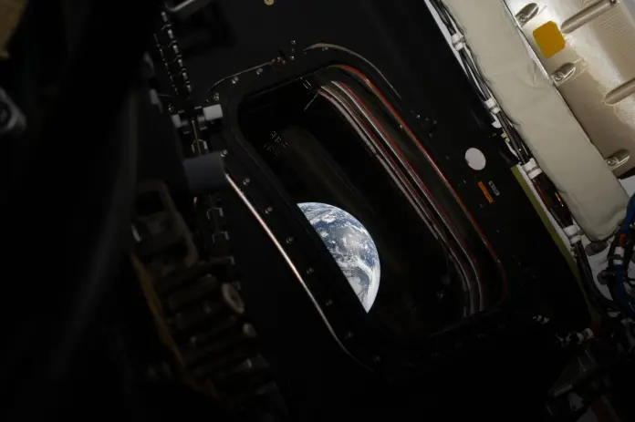 Artemis II Commander Reid Wiseman peers out of one of the Orion spacecraft's main cabin windows at Earth.