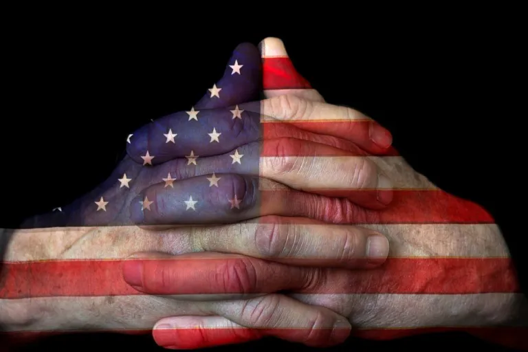American flag painted over clasped hands in prayer.