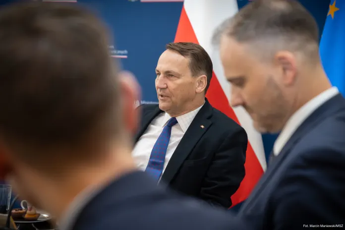 Radosław Sikorski seated at press table