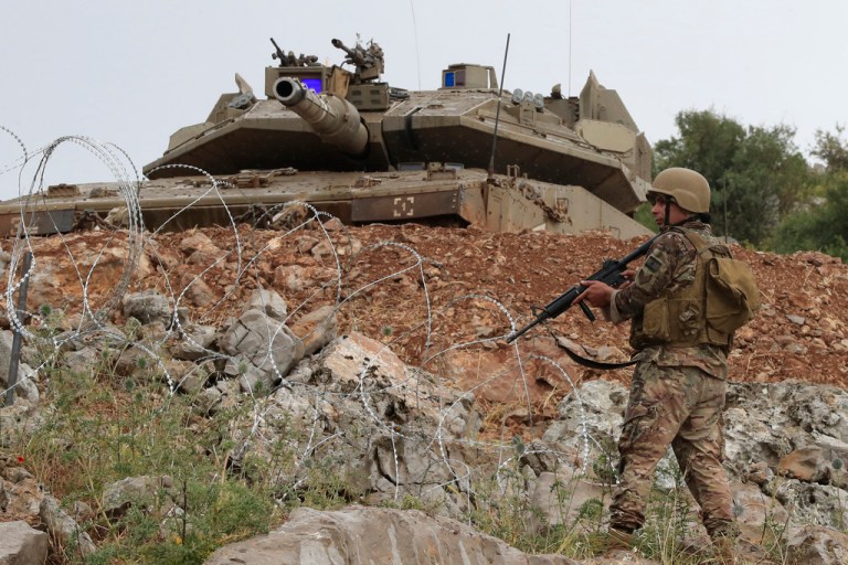 A Lebanese soldier stands in front of a Israeli Merkava tank in the disputed Kfar Chouba hills along the border, in south Lebanon, Friday, June 9, 2023.