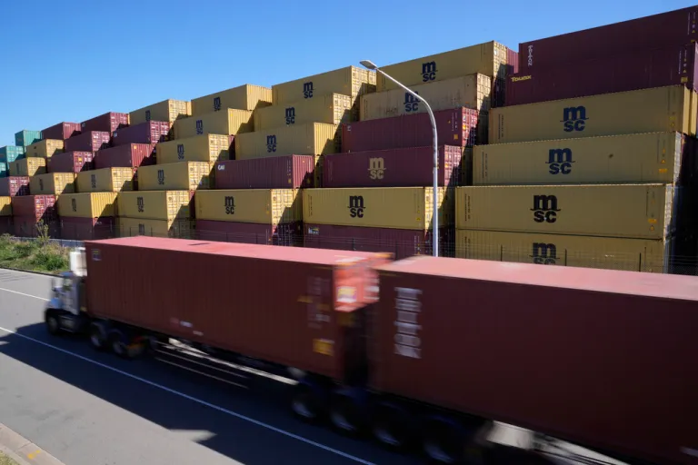 A truck drives past stacked shipping containers at Port Botany in Sydney, Australia, Monday, April 7, 2025. (AP Photo/Rick Rycroft)