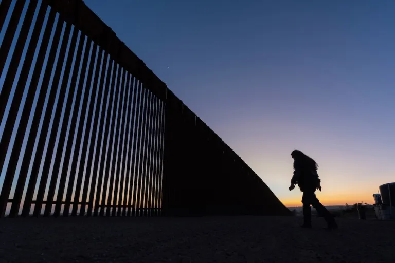A volunteer walks along a road next to the border wall separating Mexico and the United States in Jacumba Hot Springs, Calif., Jan. 19, 2025. (AP Photo/Gregory Bull)