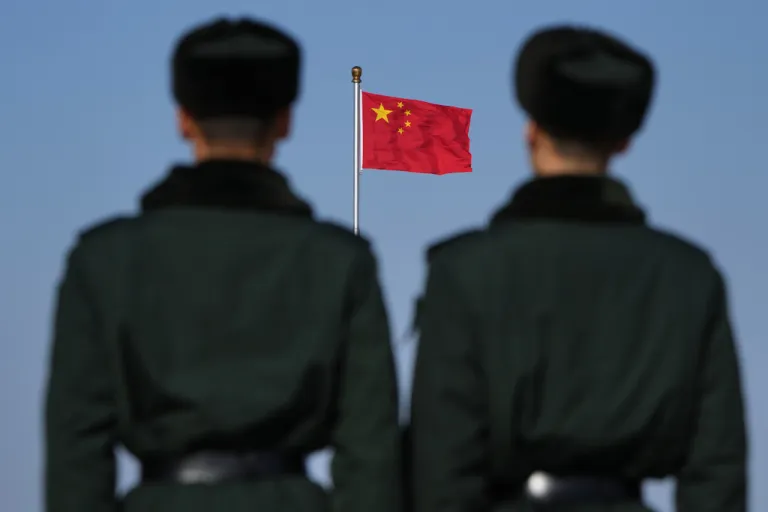 Soldiers stand watch against the national flag on Tiananmen Square