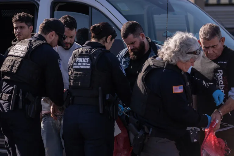ICE agents remove chains and handcuffs from a group of undocumented migrants before they are escorted across the McAllen–Hidalgo–Reynosa International Bridge in McAllen, Texas, Friday, March 13, 2026. Dozens of migrants from countries including Cuba, Venezuela, Haiti, China, Guatemala and El Salvador were handed over to Mexican authorities. (AP Photo/Felix Marquez)