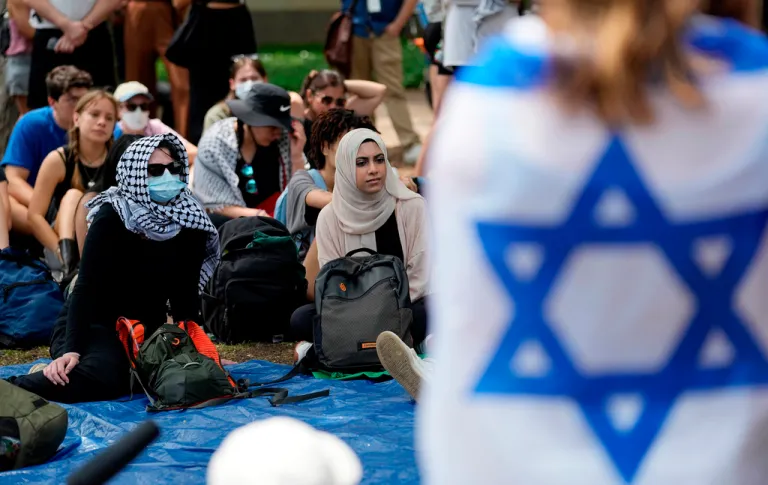 A student wrapped in an Israeli flag listens to Pro-Palestinian protesters gathered on campus at the University of Texas.
