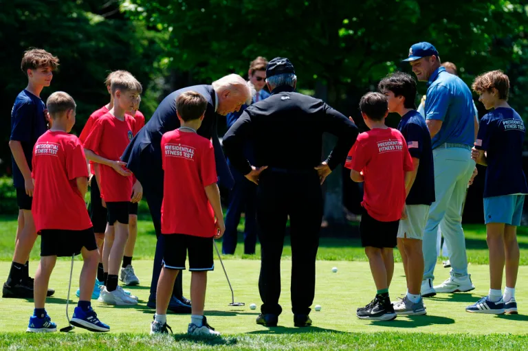 Golfers Bryson DeChambeau, right, and Gary Player, center, watch as President Donald Trump gives children putting lessons on the south lawn of the White House on May 5, 2026.