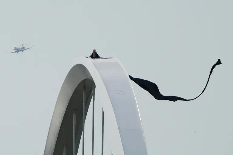 An airplane passes by as Guido Reichstadter protests atop the Frederick Douglass Memorial Bridge for the fifth day, Tuesday, May 5, 2026, in Washington. (AP Photo/Julia Demaree Nikhinson)