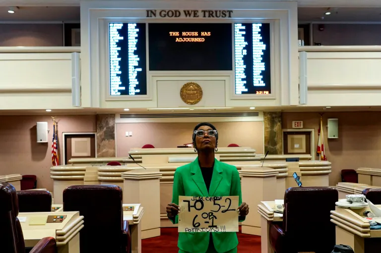 Alabama state Rep. Juandalynn Givan stands with a sign in a green jacket