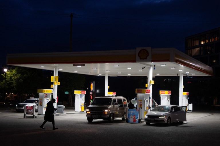 A person walks past a gas station.