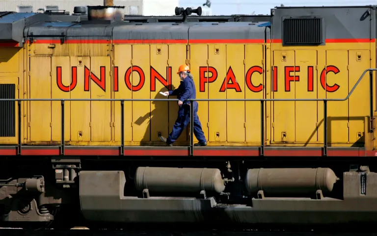 A maintenance worker walks past the company logo on the side of a locomotive in the Union Pacific Railroad fueling yard in north Denver, Oct. 18, 2006. (AP Photo/David Zalubowski, File)