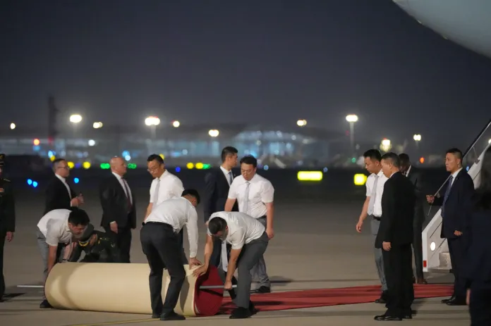 Workers roll out a red carpet as President Donald Trump arrives on Air Force One, Wednesday, May 13, 2026, at Beijing Capital International Airport in Beijing. (AP Photo/Mark Schiefelbein)