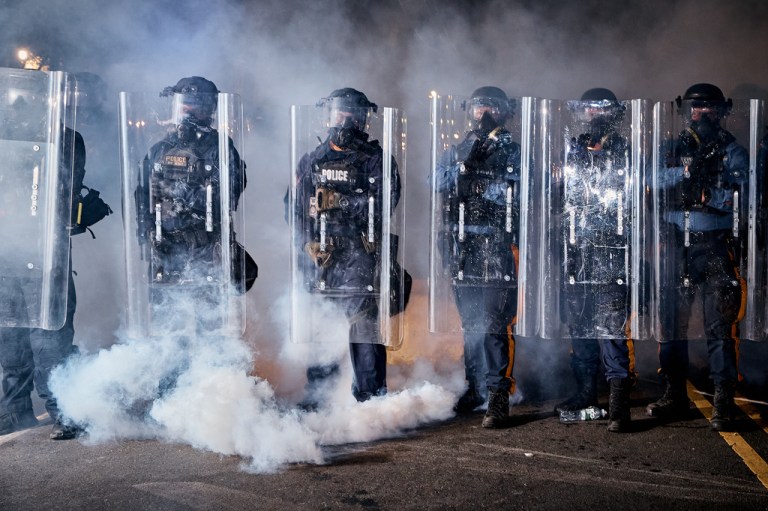 State police officers stand behind shields