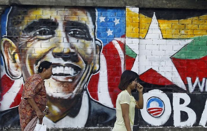 Pedestrians walk by a wall adorned with a graffiti showing US President Barack Obama in downtown Yangon on November 11, 2012.  Myanmar's government has said it "warmly welcomes" the historic visit of President Barack Obama on November 19, expressing hope his trip will bolster the nation's political reform drive.  AFP PHOTO/Ye Aung Thu        (Photo credit should read Ye Aung Thu/AFP via Getty Images)