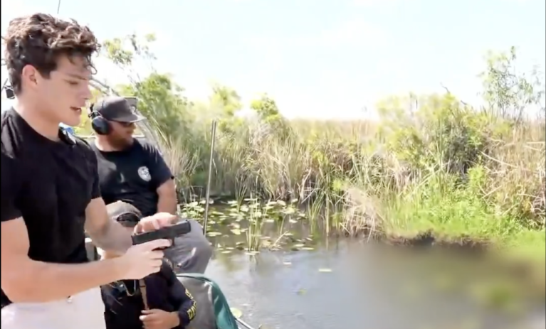 Streamer Clavicular, whose real name is Braden Peters, seen during a live stream holding a gun after allegedly shooting an alligator in the Florida Everglades.