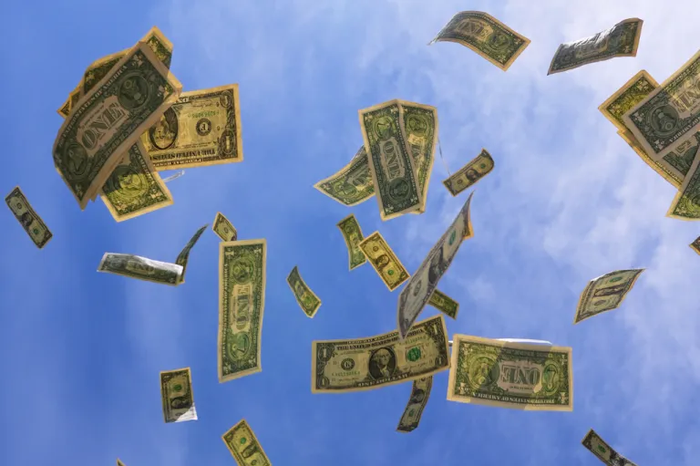 U.S. $1 bills are seen against the sky.