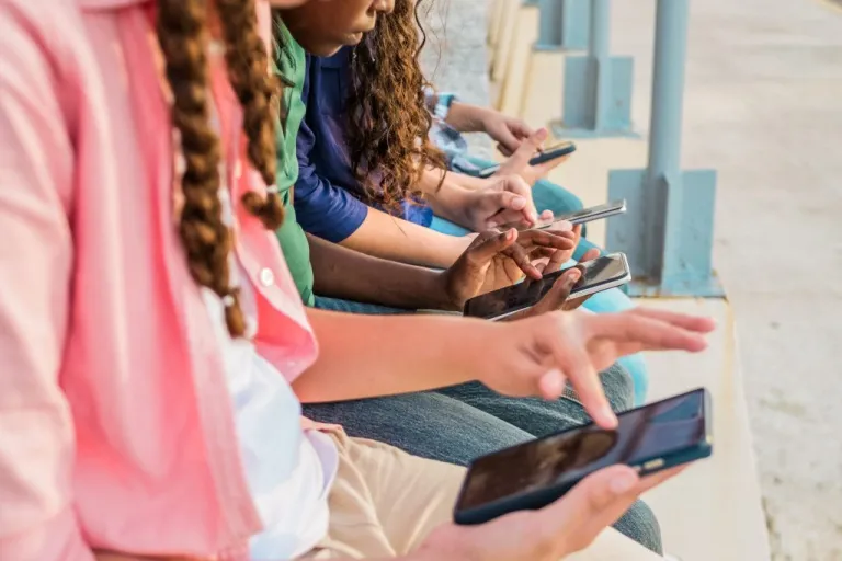 Close-up of teenage friends using mobile phone outdoors