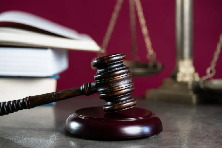 A deep brown wooden gavel is propped up on a table with books behind in (Getty Images).