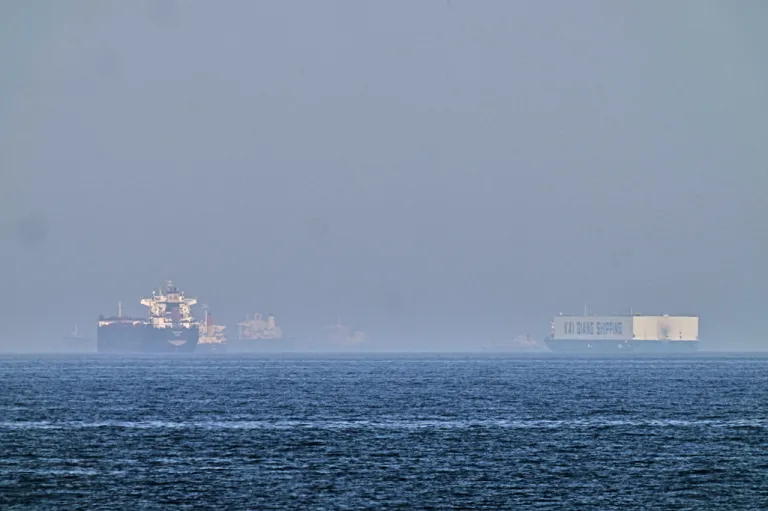 A tanker, left, and a car carrier are anchored at sea in the Gulf of Oman near the Strait of Hormuz, as seen from the coast near Khor Fakkan, United Arab Emirates.
