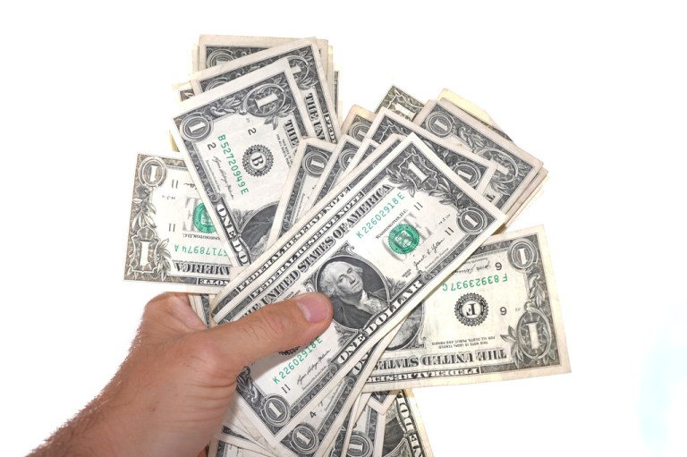 U.S. $1 bills are held.