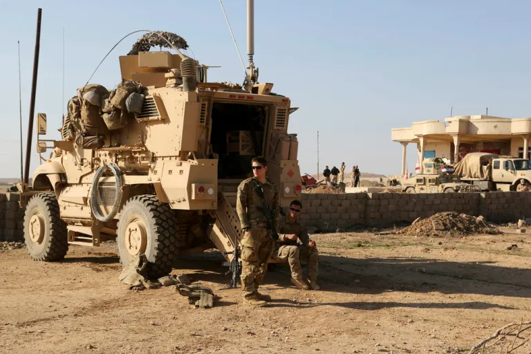 U.S. Army soldiers stand outside their armored vehicle