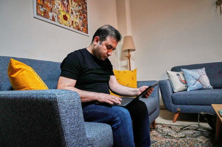 Mehdi Alishir looks at his laptop in his living room in Tehran, Iran.